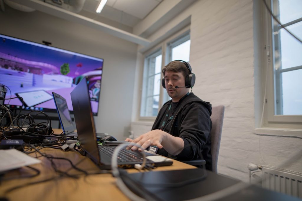A person wearing headphones and sitting at a desk with a computer

Description automatically generated with medium confidence